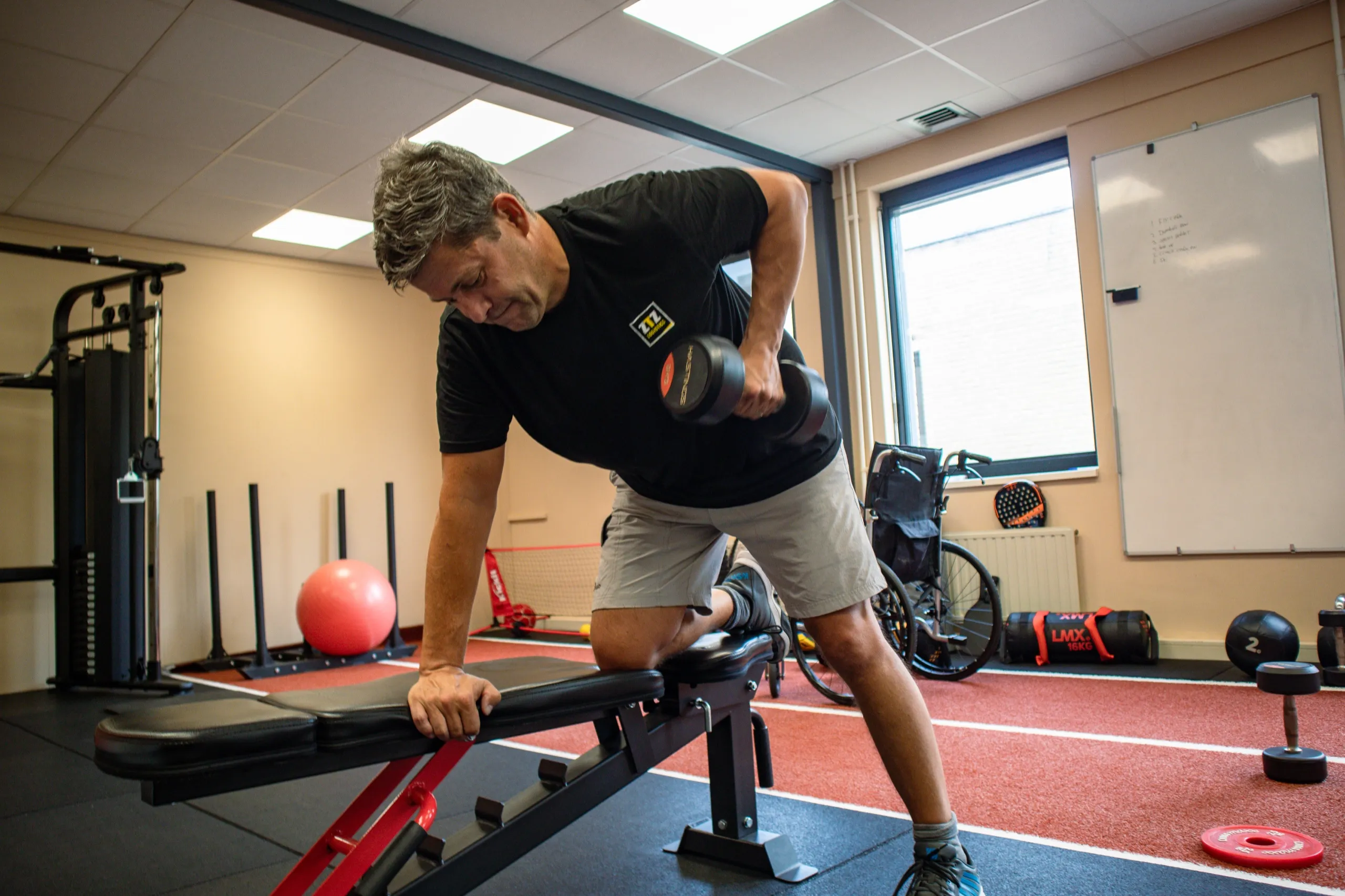 Een cliënt traint met een dumbbell op een bankje in de lichte studio van Bekafit